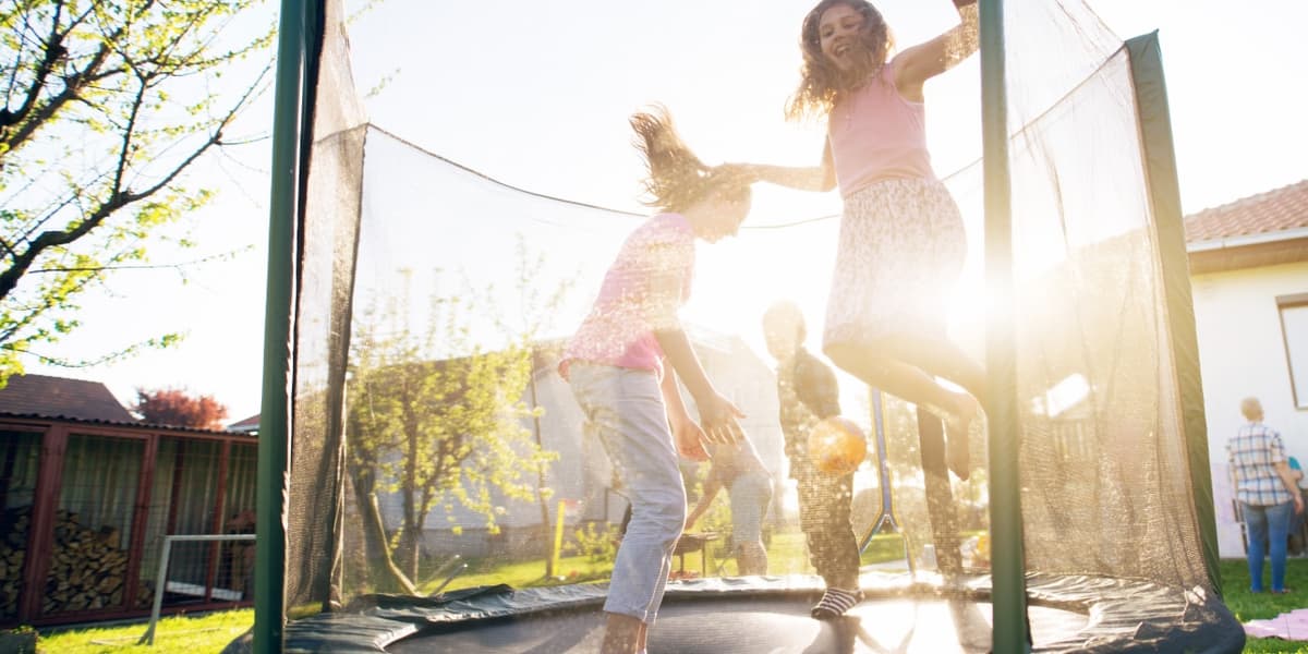 Kinderen springen op trampoline in de tuin van hun huis