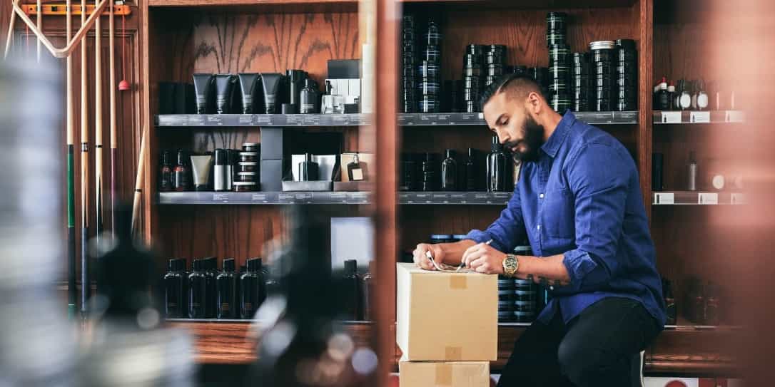 Barbier staat in zijn zaak en controleert een bestelling van producten