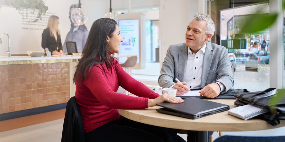 Mannelijke verzekeringsadviseur zit aan tafel tegenover vrouwelijke klant