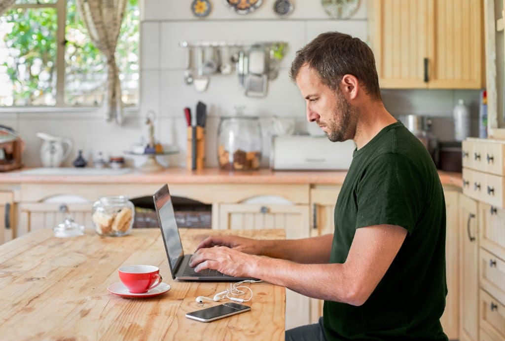Man werkt aan keukentafel met zijn laptop